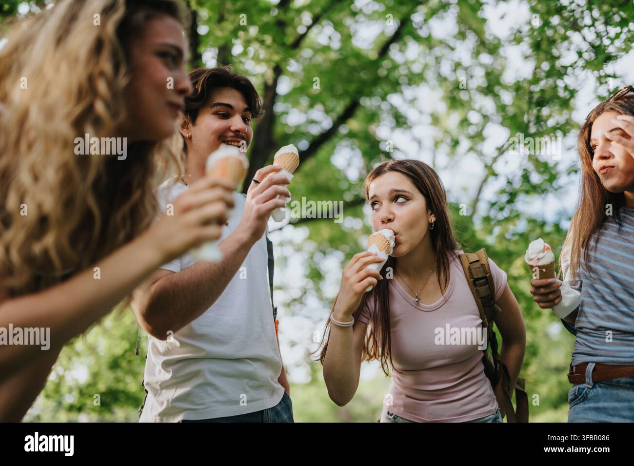 Teen-Freunde essen zusammen Eis in einem sonnigen Park und genießen ein lässiges Sommer-Treffen Stockfoto