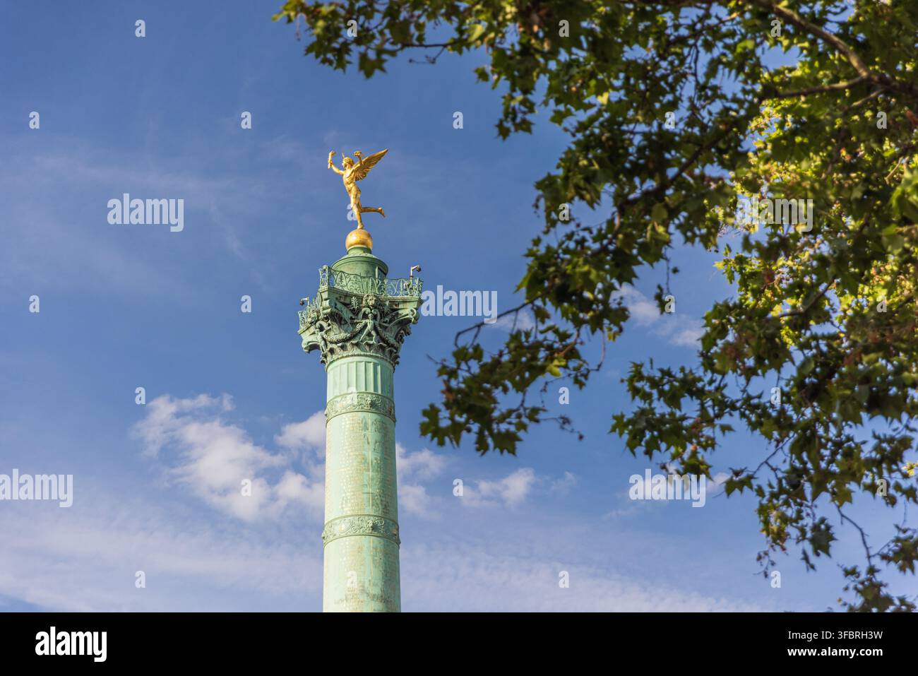 Goldener Geist der Freiheit oben auf der Julisäule, eingerahmt von grünen Blättern am Place de la Bastille. Stockfoto