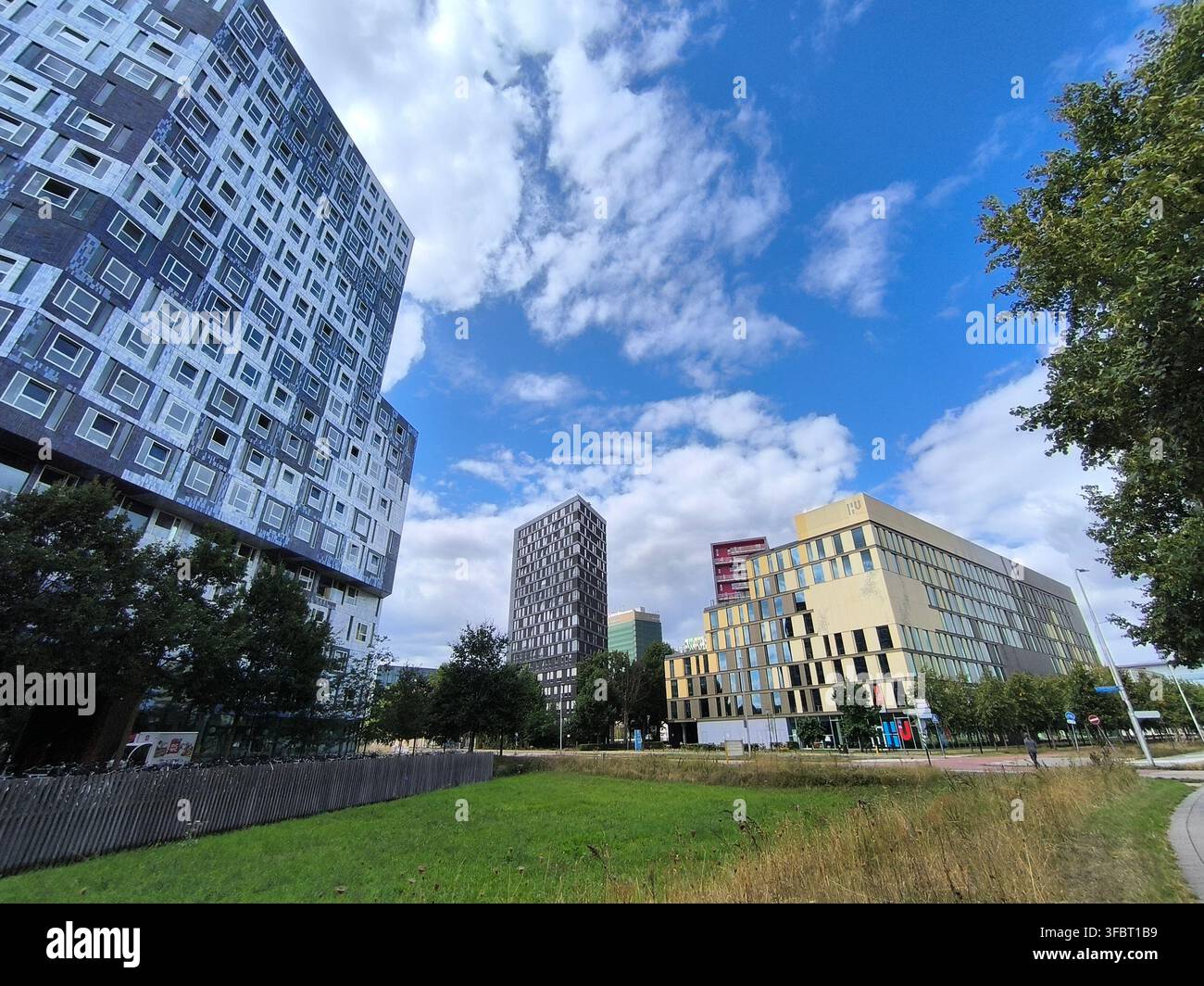 Moderne städtische Wohn- und Bildungsgebäude mit blauem Himmel, der mit Wolken übersät ist, grüner Park im Utrecht Science Park, Niederlande. Stockfoto