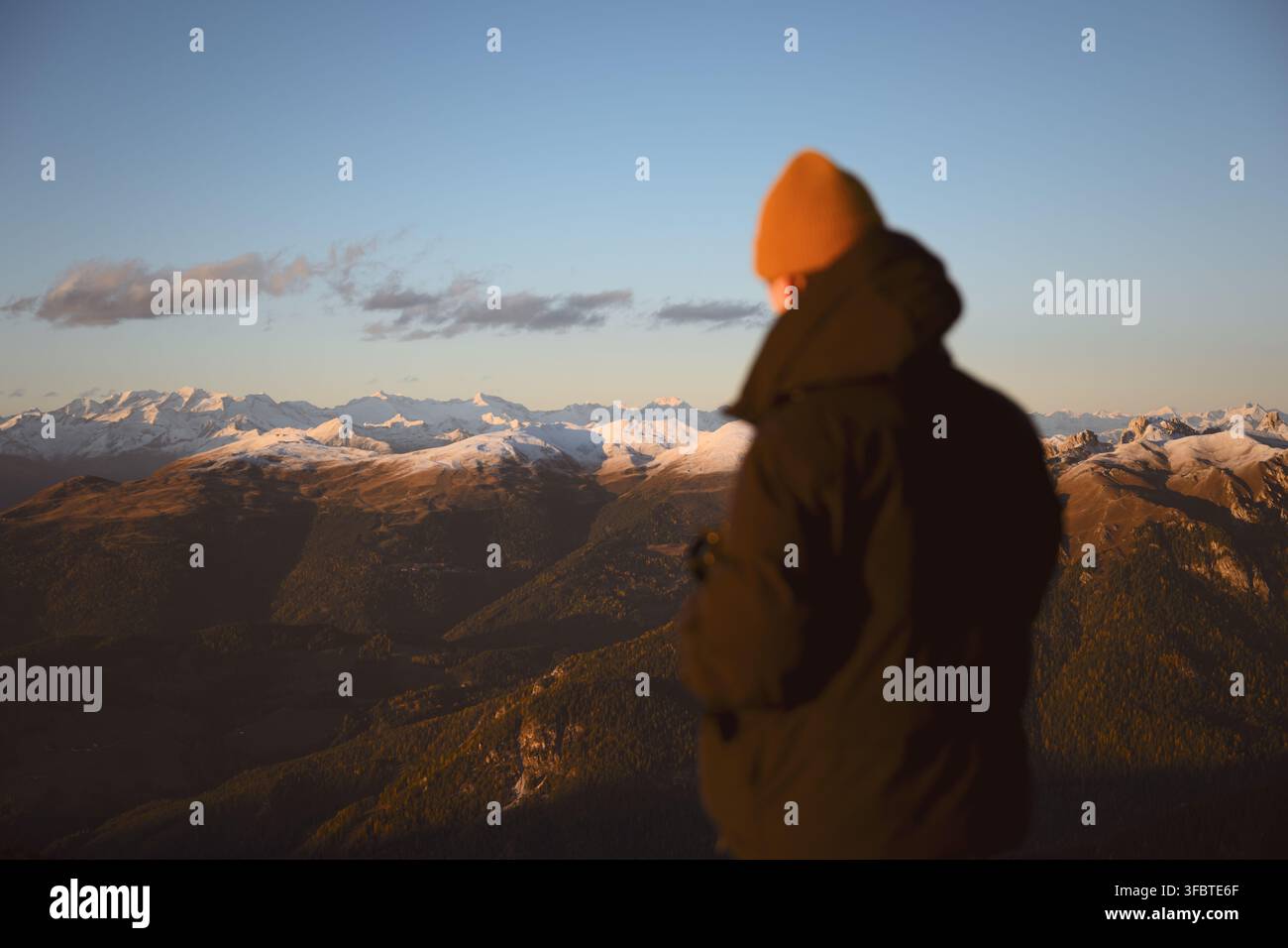 Person, die Bergketten überblickt, die vom Sonnenlicht im Dolomiten beleuchtet werden. Malerische Alpenlandschaft mit geschichteten Bergrücken und Herbstfarben Stockfoto