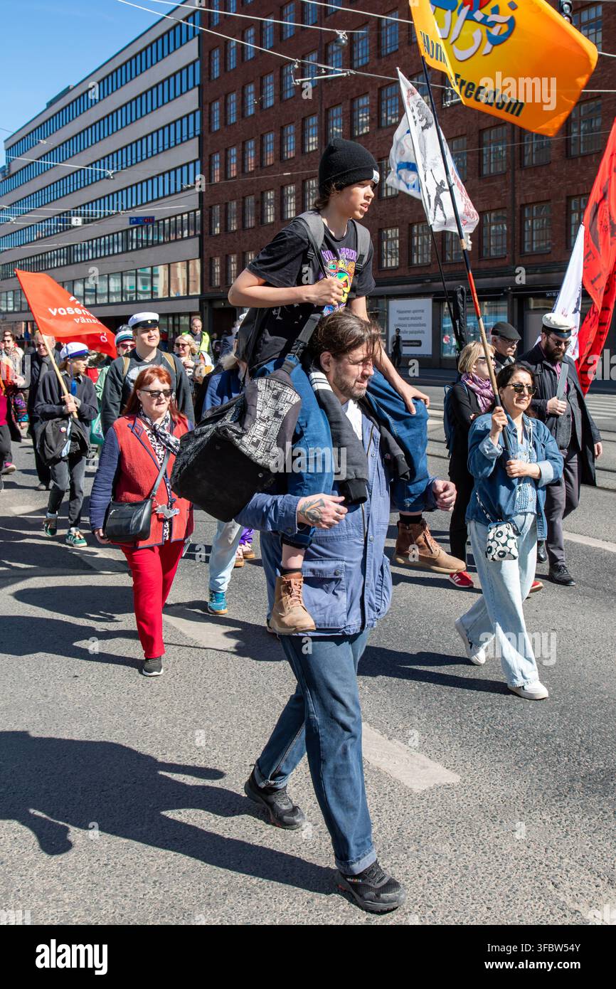Kind, das auf den Schultern von Erwachsenen bei einem Maifeier-Marsch im Hakaniemi-Viertel von Helsinki, Finnland, reitet Stockfoto