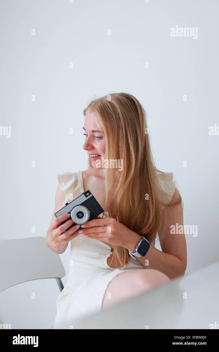 Lächelnde junge Frau hält eine Kompaktkamera und präsentiert Kopierplatz, Fotografie-Hobby und kreatives Lebensstil-Konzept. Stockfoto