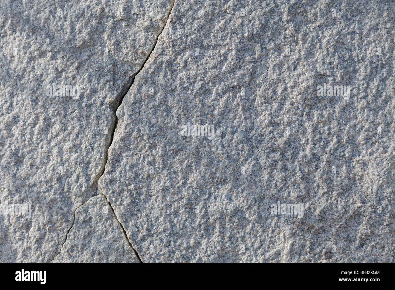Graue Steinoberflächentextur mit natürlichem Rissmuster, feiner mineralischer Körnung und verwittertem felsigem Aussehen Stockfoto