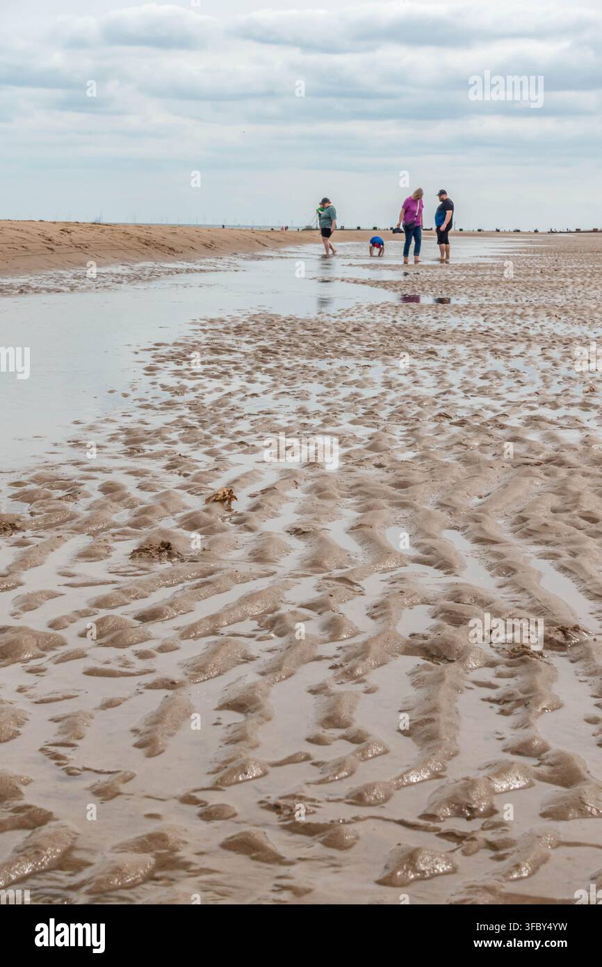 Menschen paddeln in einem Pool, der am Strand von Mablethorpe in Lincolnshire durch Wasser geschaffen wurde, das von einer Sandbank aufgestaut wurde Stockfoto