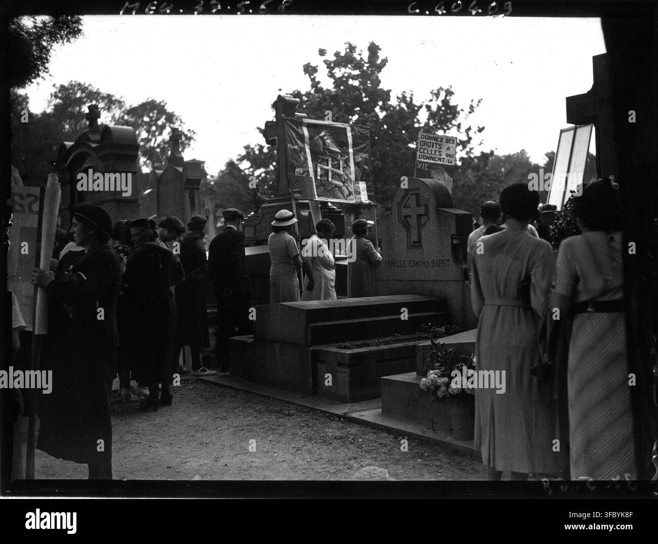 Eine Gruppe von Menschen, die sich um Gräber auf dem Friedhof Père Lachaise versammelt haben, um den Jahrestag der Pariser Kommune zu gedenken, mit einem Banner mit der Aufschrift "Donnez des droits à celles qui donnent la vie" und "Famille Edmond Bapst", in einer Presse von 1937. Stockfoto