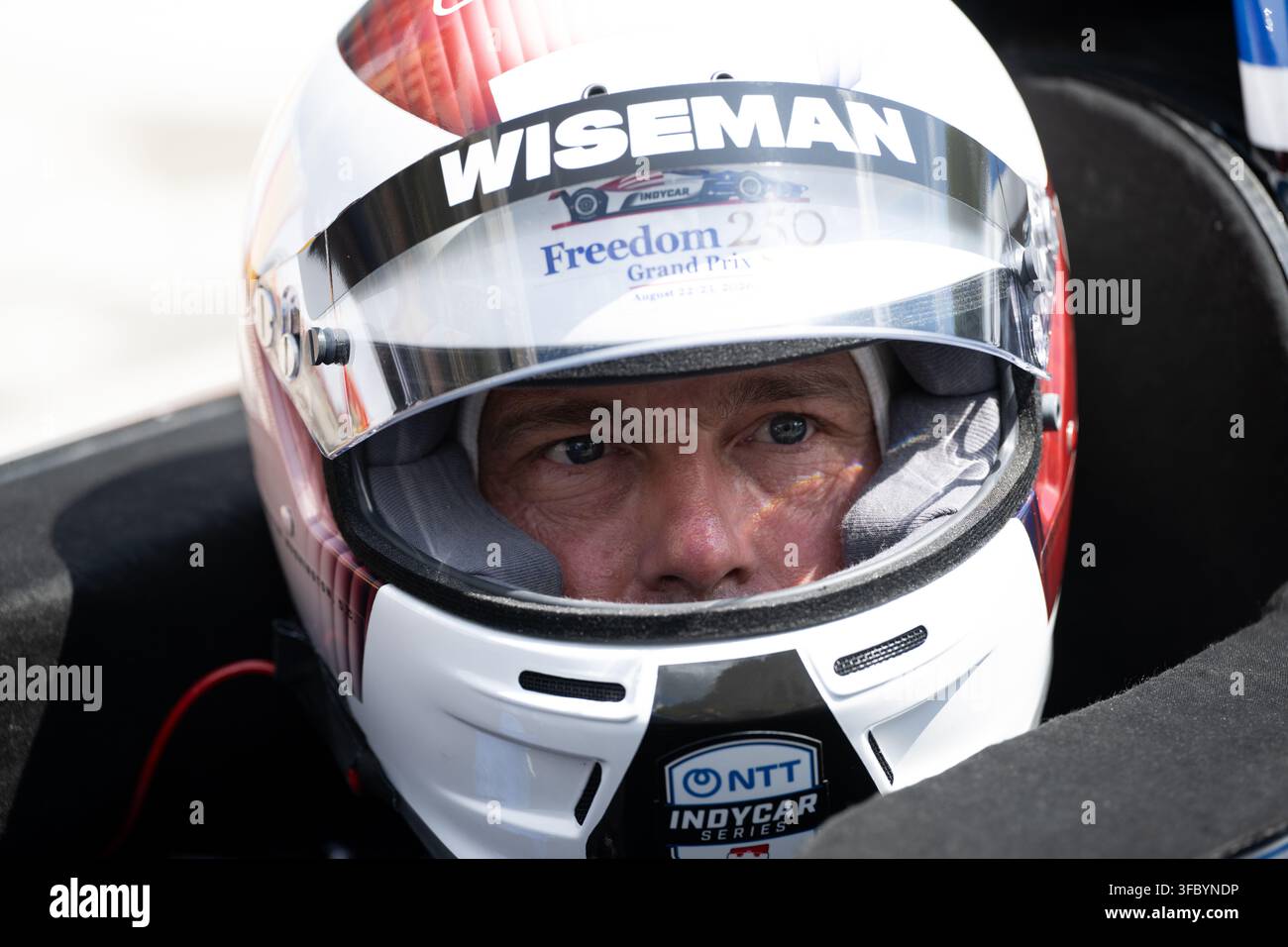 Washington, Vereinigte Staaten. 23. August 2026. NASA-Astronaut Reid Wiseman, Kommandant von Artemis II, trägt einen Rennhelm und sitzt in einem Zweisitzer-IndyCar, während er sich darauf vorbereitet, dass Fahrer Conor Daly ihn während einer Übungseinheit vor dem Freedom 250 Grand Prix am 22. August 2026 in Washington, D.C., eine Runde auf der Strecke fährt. Credit: Joel Kowsky/NASA Photo/Alamy Live News Stockfoto