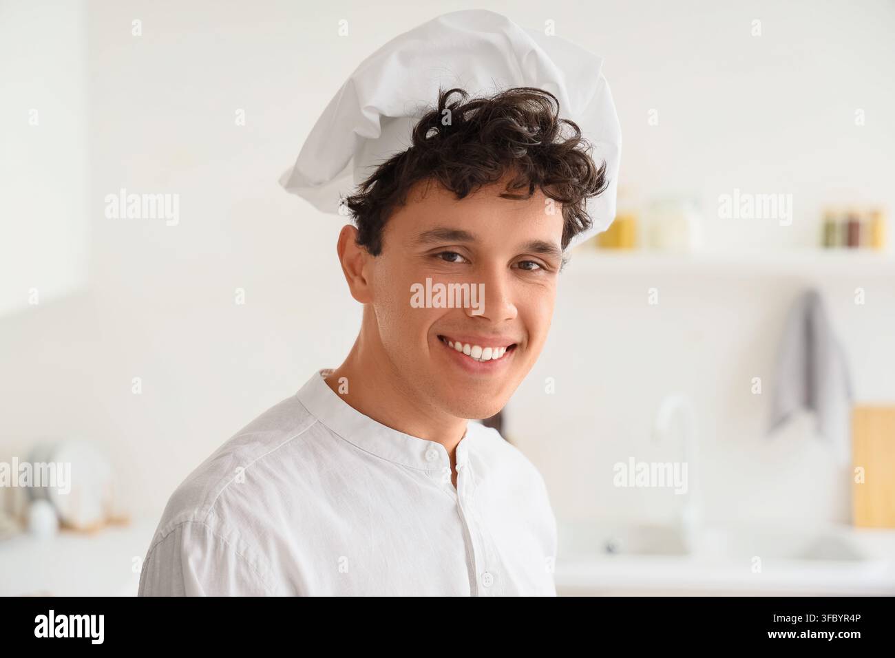 Konzept für eine kulinarische Karriere und professioneller Koch, lächelnder junger Mann mit Kochmütze arbeitet in einer modernen Küche Stockfoto