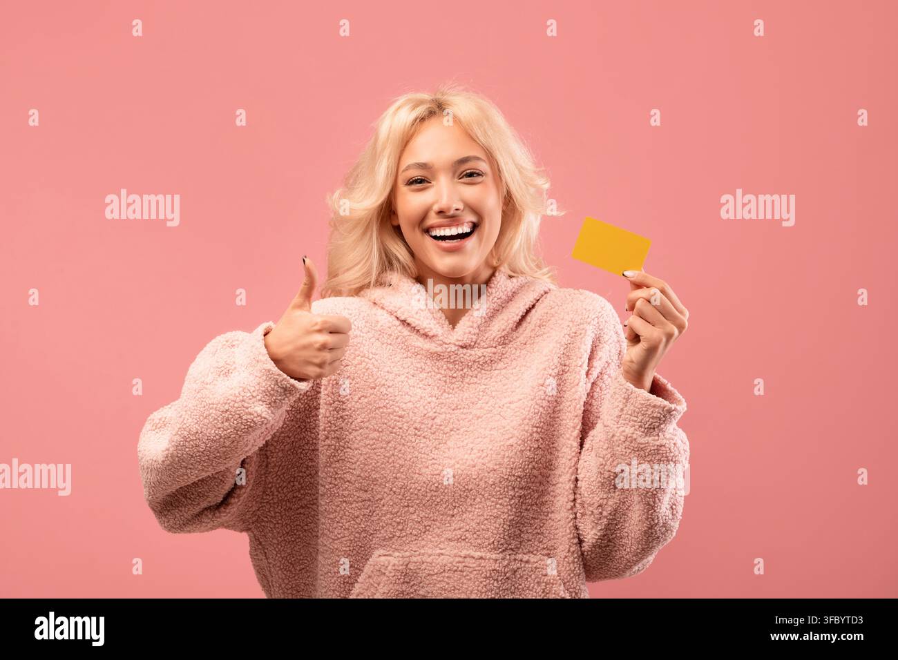 Zufriedene junge Frau hält gelbe Karte und zeigt Daumen hoch, positives Lebensstil-Konzept Stockfoto