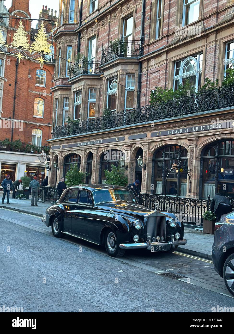 Ein klassischer schwarzer Vintage-Rolls-Royce, der vor dem The Audley Public House Pub in Mayfair geparkt ist, der für Weihnachten geschmückt ist. London, UK. - Smartphone-aufgenommenes Stockfoto
