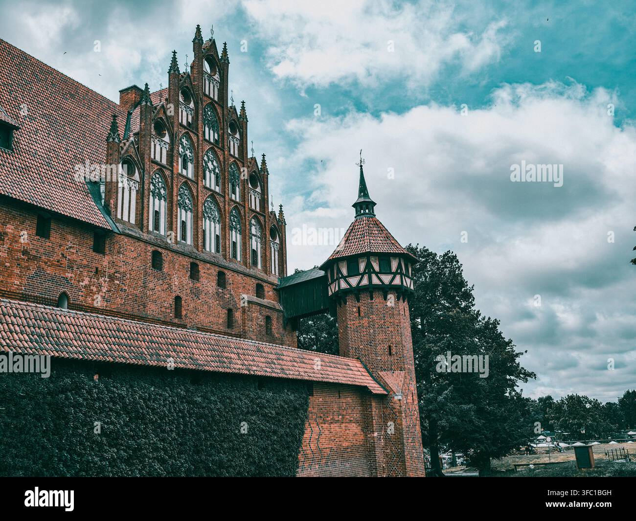 Eine niedrige Außenansicht der historischen Burg Malbork in Polen, die ihre kunstvolle rote Backstein-Gotik und einen alten Turm zeigt Stockfoto