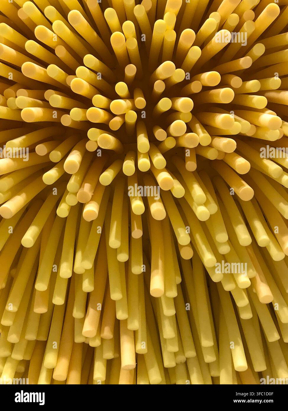 Dichte gelbe Schaumstoffstäbe bilden einen abstrakten radialen strukturierten Hintergrund Stockfoto