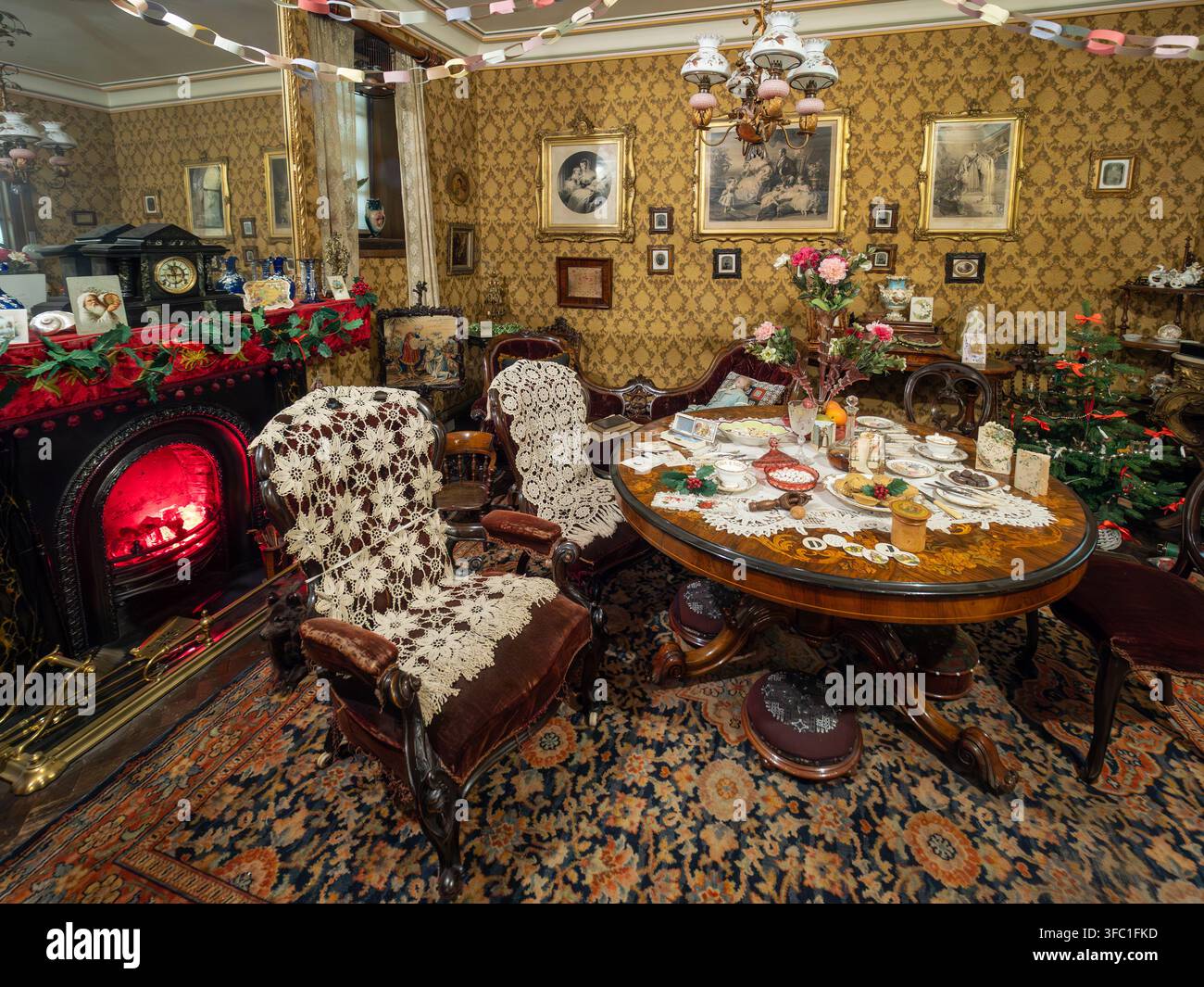 Viktorianisches Wohnzimmer mit Weihnachtsdekoration, geschmücktem Tisch und glühendem Kamin im York Castle Museum in York, England. Stockfoto