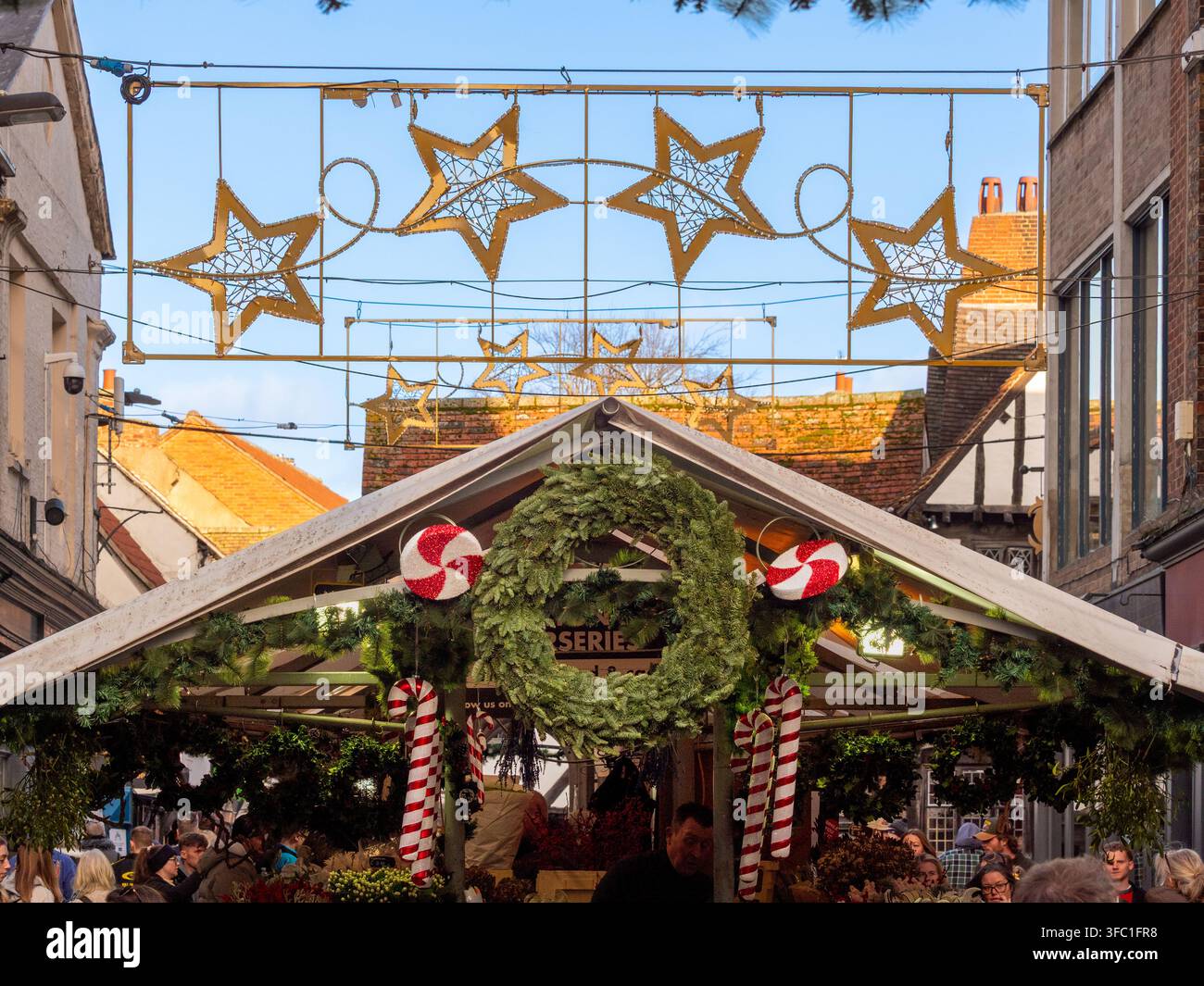 Festliche Lichter, Kränze und Einkäufer auf dem York-Weihnachtsmarkt in York, North Yorkshire, England. Stockfoto