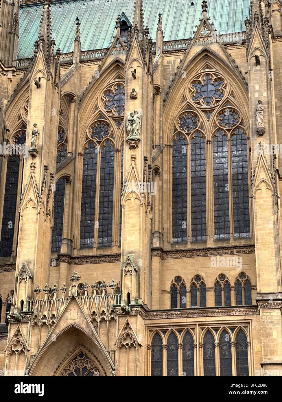 Gotische Kathedralen-Außenarchitektur mit aufwendigen Steinschnitzereien und gewölbten Fenstern. Prächtige gotische Kathedralenfassade mit kunstvollen Steinverzierungen - Smartphone-aufgenommenes Stockfoto