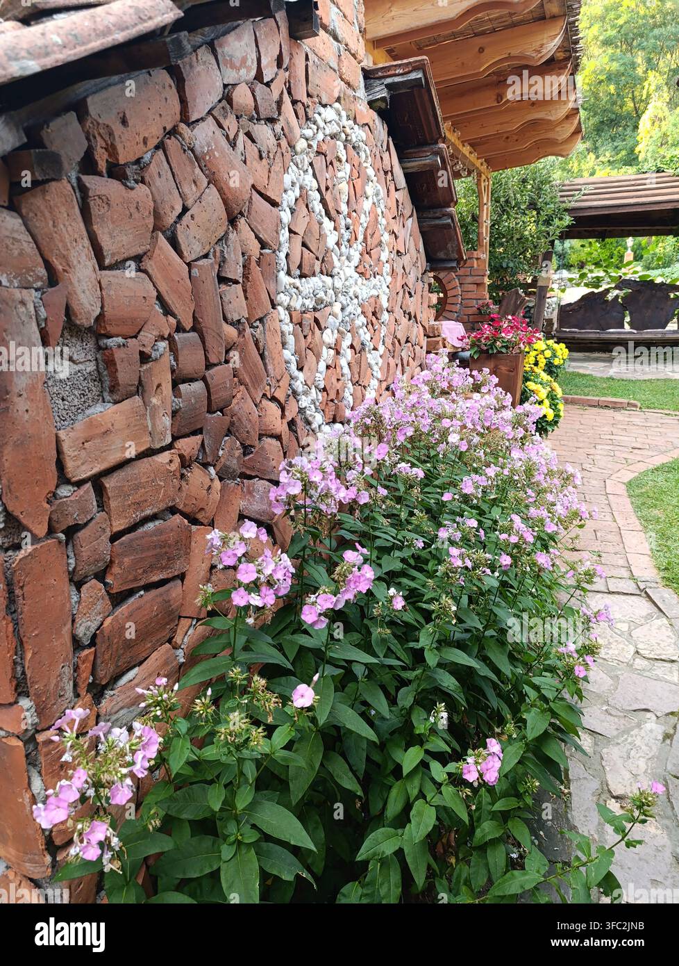 Rustikale Ziegelgartenmauer mit Blumen in der serbischen Landschaft Stockfoto