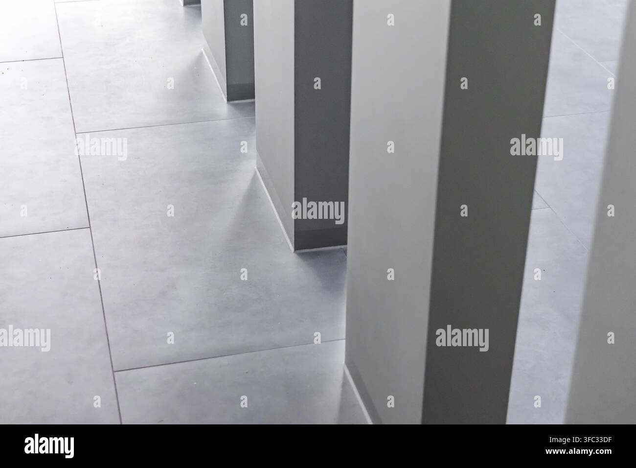 Eine minimalistische architektonische Perspektive eines zeitgenössischen Flurs mit großformatigen Fliesen und sich wiederholenden vertikalen Elementen Stockfoto