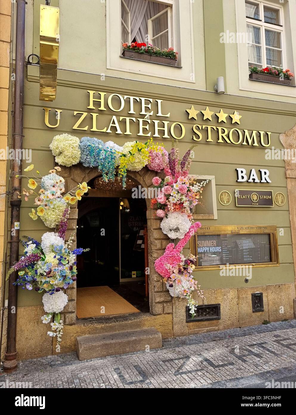 Prag, Tschechien – 28. Juli 2026: Blütengeschmückter Eingang des Hotels U Zlateho Stromu mit Bar im historischen Zentrum Prags. Stockfoto
