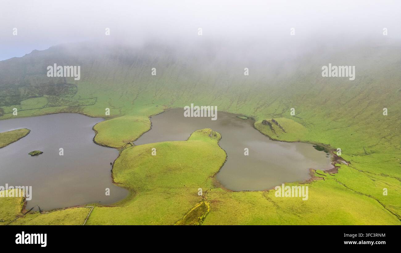 Corvo, Azoren, Portugal Luftaufnahme von nebelbedeckten Vulkansseen, die in üppigen grünen Hügeln eingebettet sind. Nebel bedeckt die Landschaft und erzeugt ein weiches, ätherisches Li Stockfoto