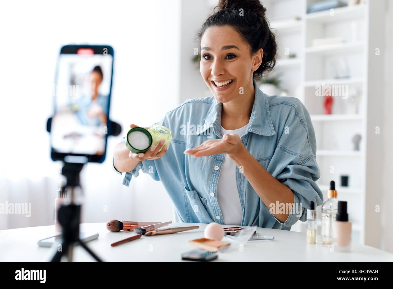 Glückliche junge Frau zeigt Hautpflegeprodukt zu Hause, Wellness-Konzept Stockfoto