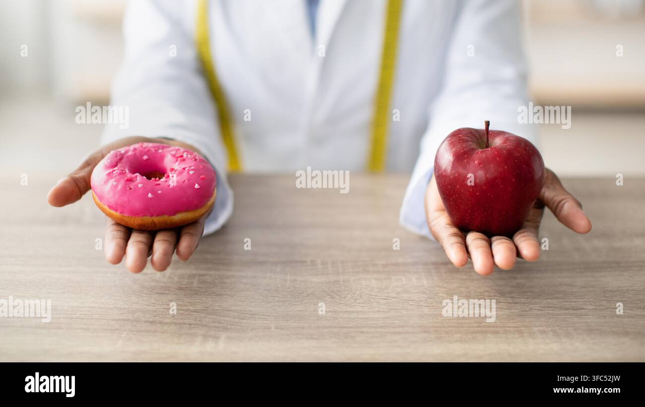 Person hält rosa Donut und roten Apfel in den Händen, Konzept für gesunde Entscheidungen, nicht erkennbar Stockfoto