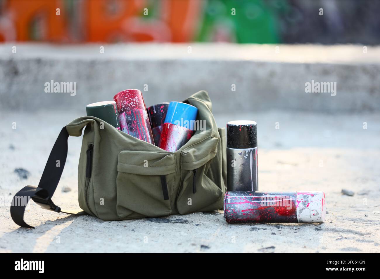 Urbane Kunst und Straßenkultur, Graffiti-Sprühfarbe-Dosen in einer Tasche auf Beton, kreativer Ausdruck und jugendlicher Aufstand Stockfoto