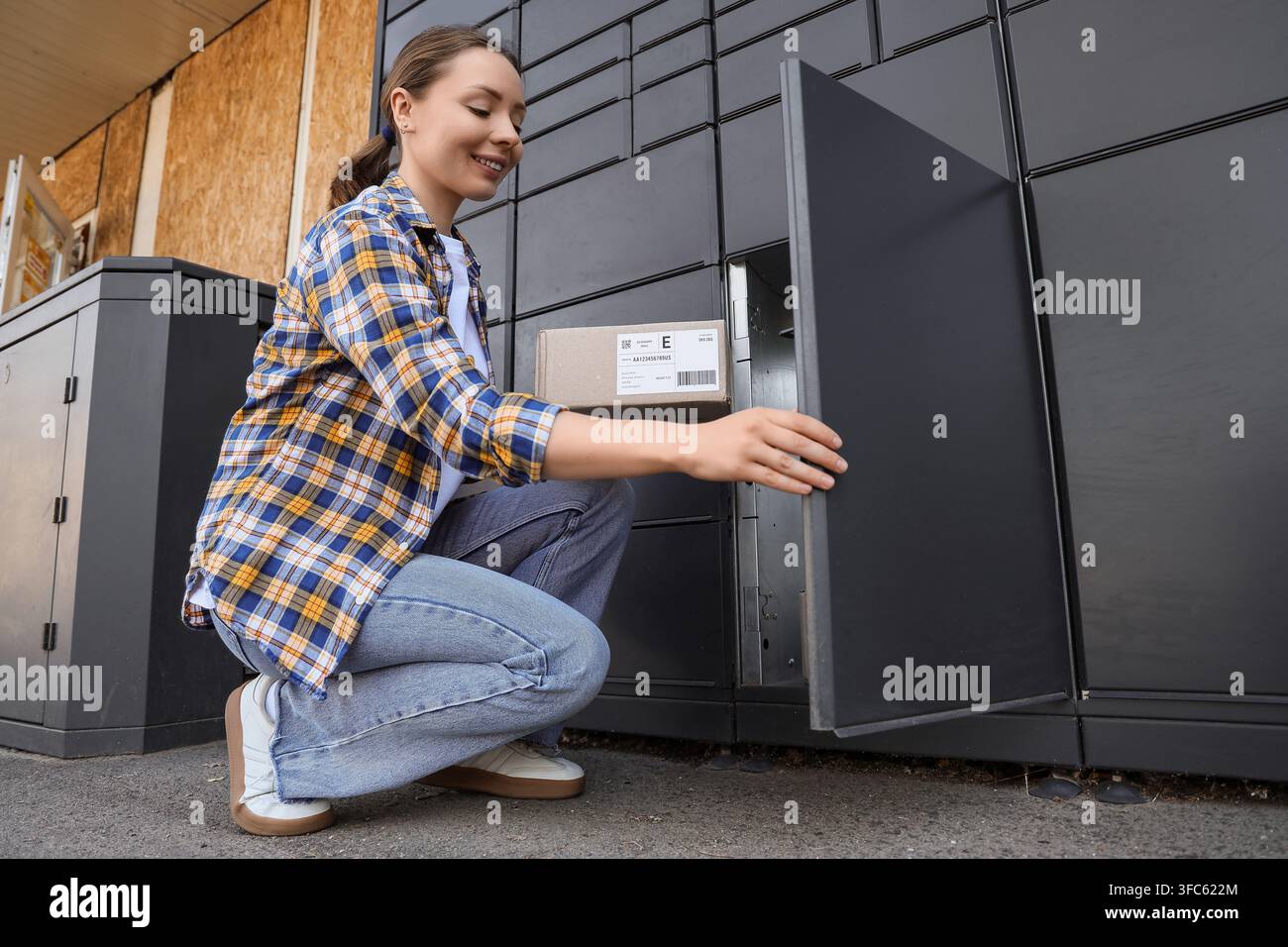 E-Commerce und Bequemlichkeit beim Online-Shopping, Frau holt Paket von einem automatisierten Schließfach für den modernen Lieferservice ab Stockfoto