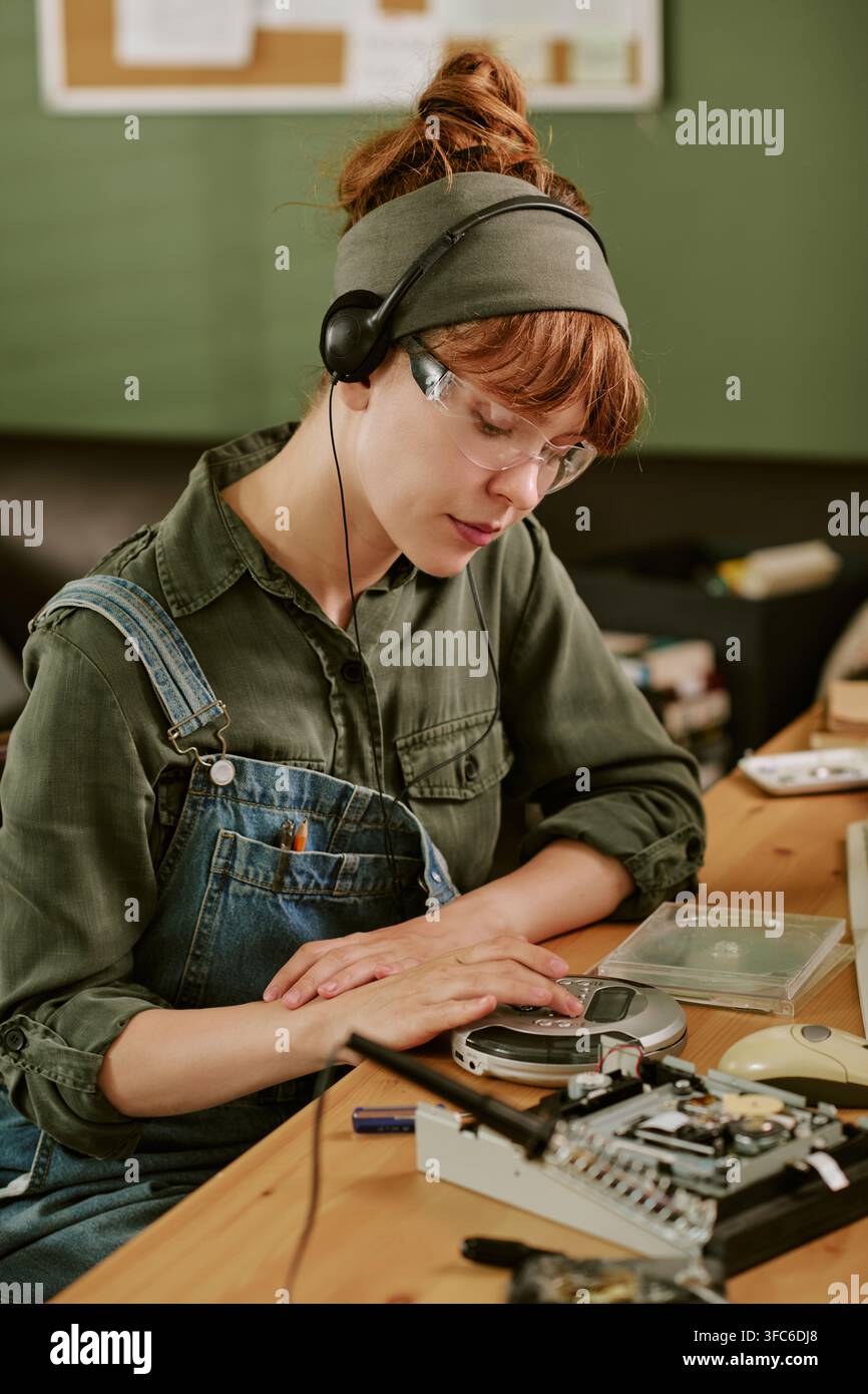 Frau hört einen tragbaren CD-Player in einem Retro-Büro Stockfoto