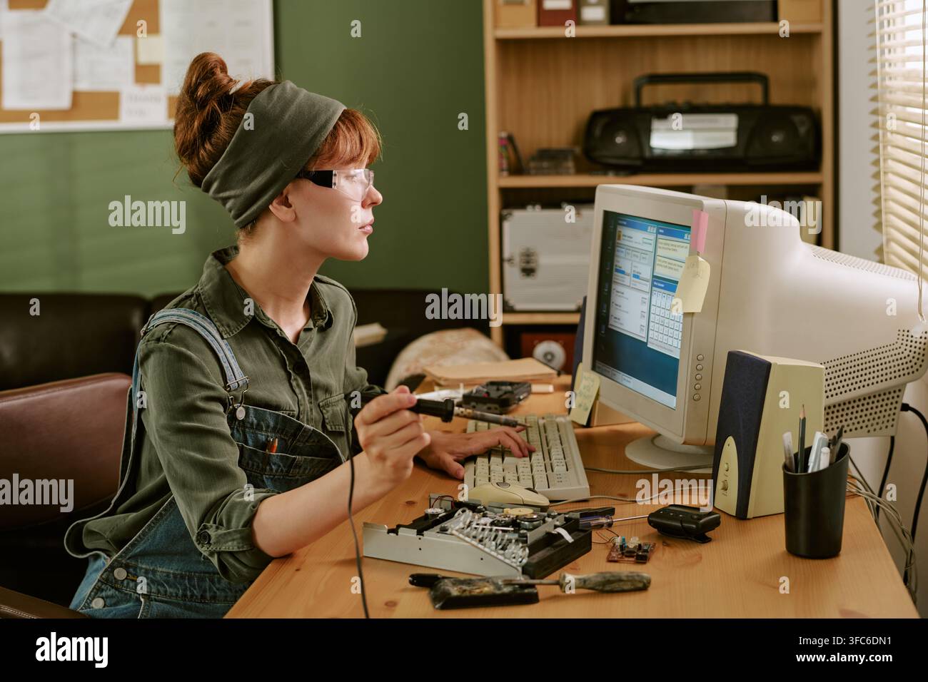 Frau repariert Computerhardware in einer Retro-Büro-Einstellung Stockfoto