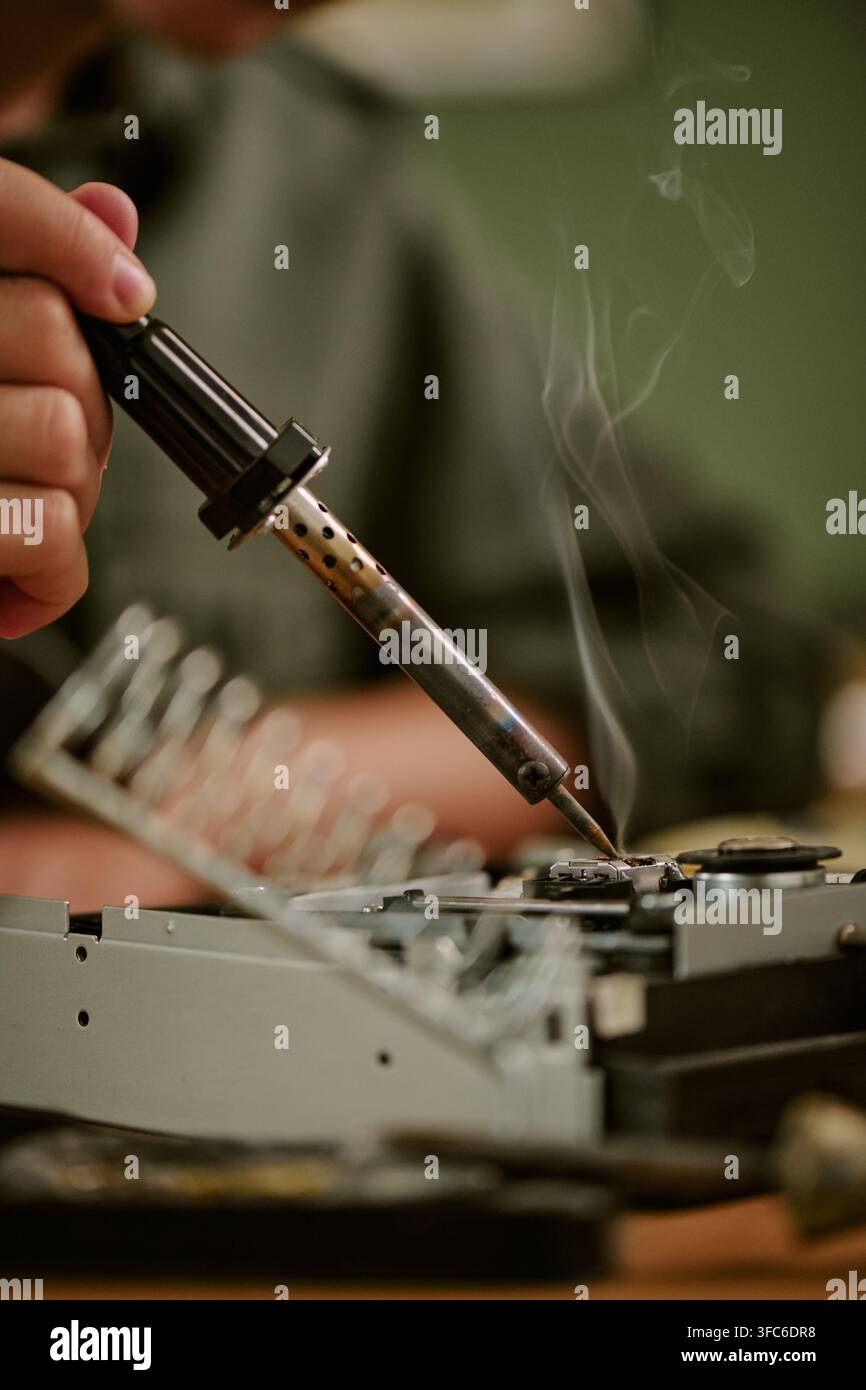 Arbeiter lötet ein Vintage-Elektronikgerät in einem Retro-Büro Stockfoto