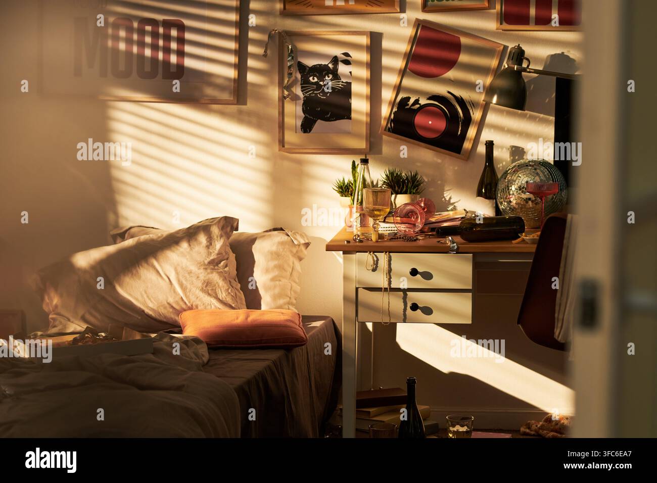 Unordliches Studenten-Schlafzimmer nach der Party mit goldenem Sonnenlicht Stockfoto