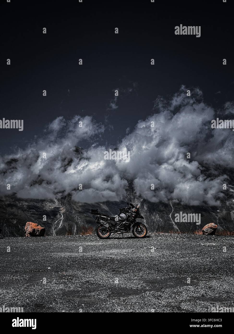 Abenteuer-Motorrad mit Blick auf eine dramatische Berglandschaft und Gewitterwolken in den österreichischen Alpen - Smartphone-aufgenommenes Stockfoto