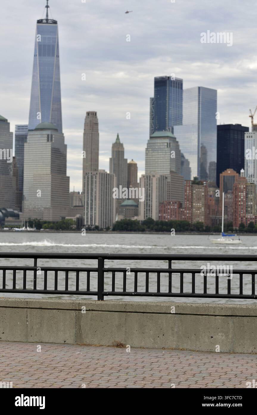 Promenade-Zaun im Hochformat lenkt die Aufmerksamkeit auf die Wolkenkratzer von Manhattan, Moody Clouds, New York Stockfoto