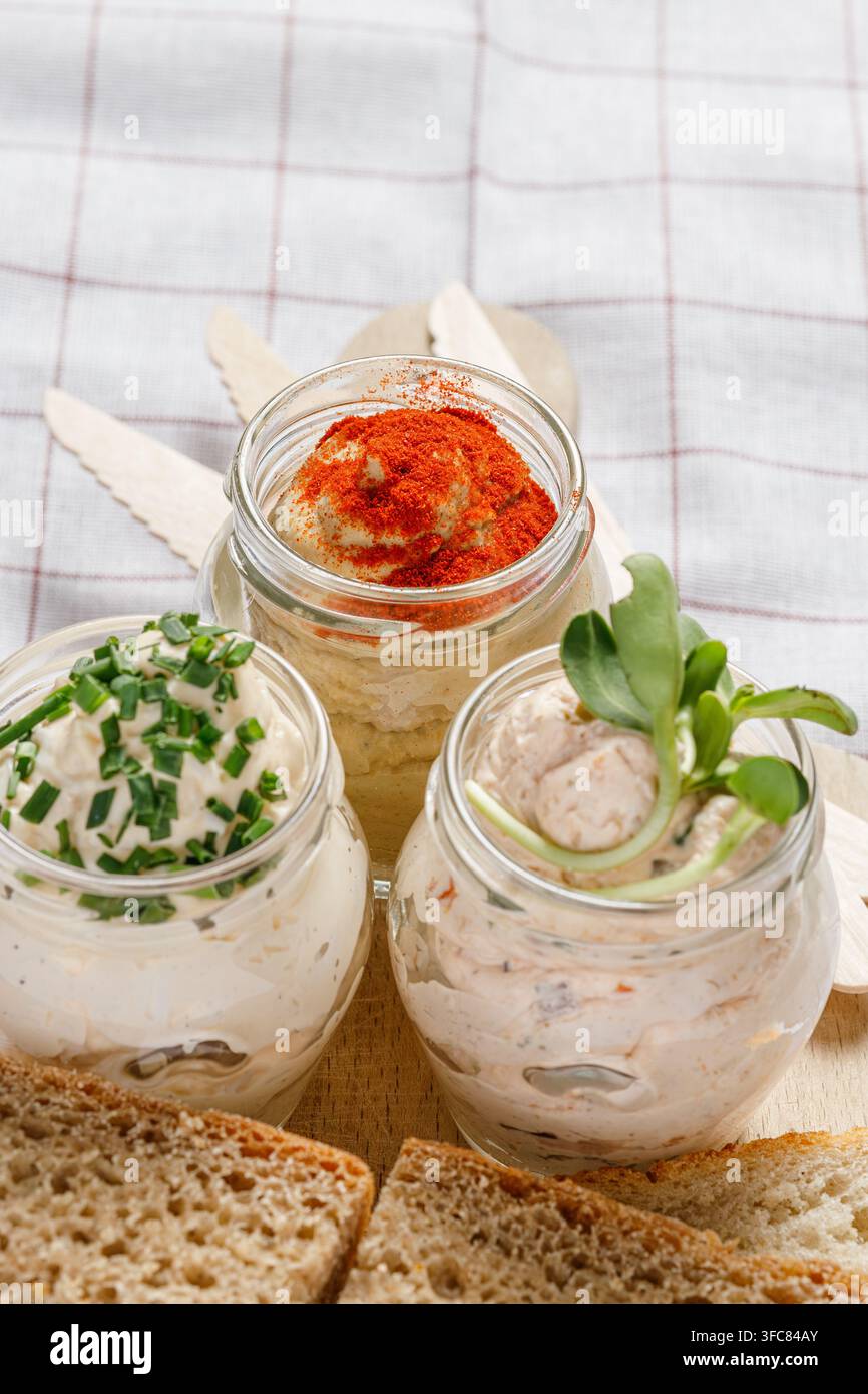Scheiben frisches Brot und Aufstriche in Gläsern auf Schneidebrett Stockfoto