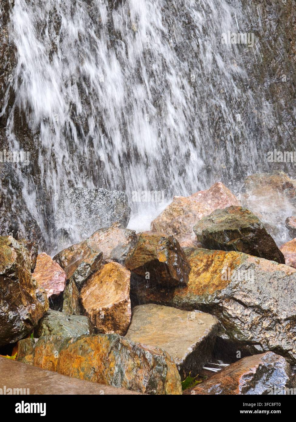 Nahaufnahme eines frischen Wasserfalls, der über farbenfrohe Felsen fließt - Smartphone-aufgenommenes Stockfoto