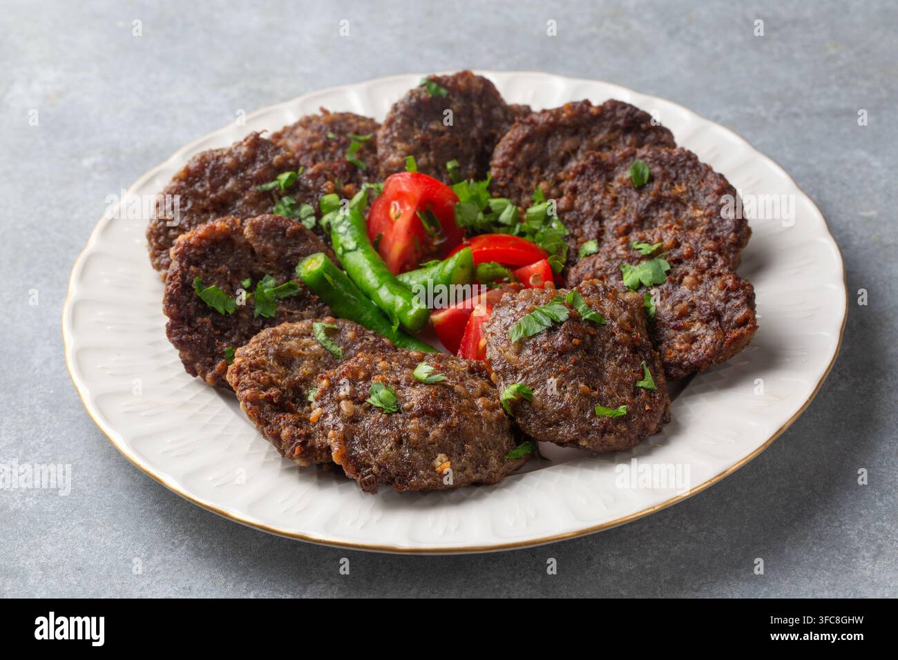 Traditionelle türkische gegrillte Fleischbällchen Kofte - Akcaabat kofte serviert mit frischen Tomaten und Paprika Stockfoto