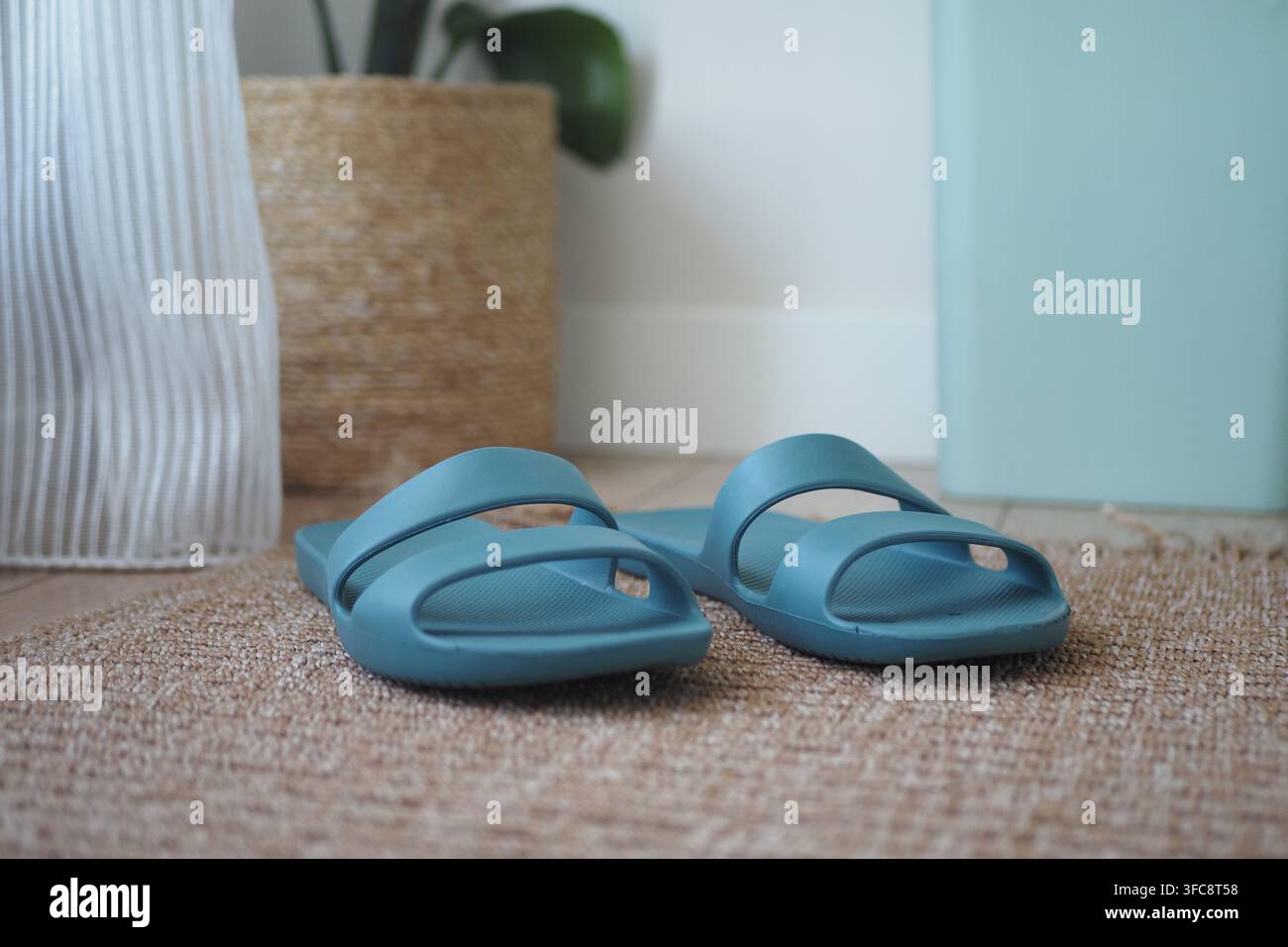 Blaue Sandalen, die auf einer gewebten Matte in einem Raum platziert sind Stockfoto