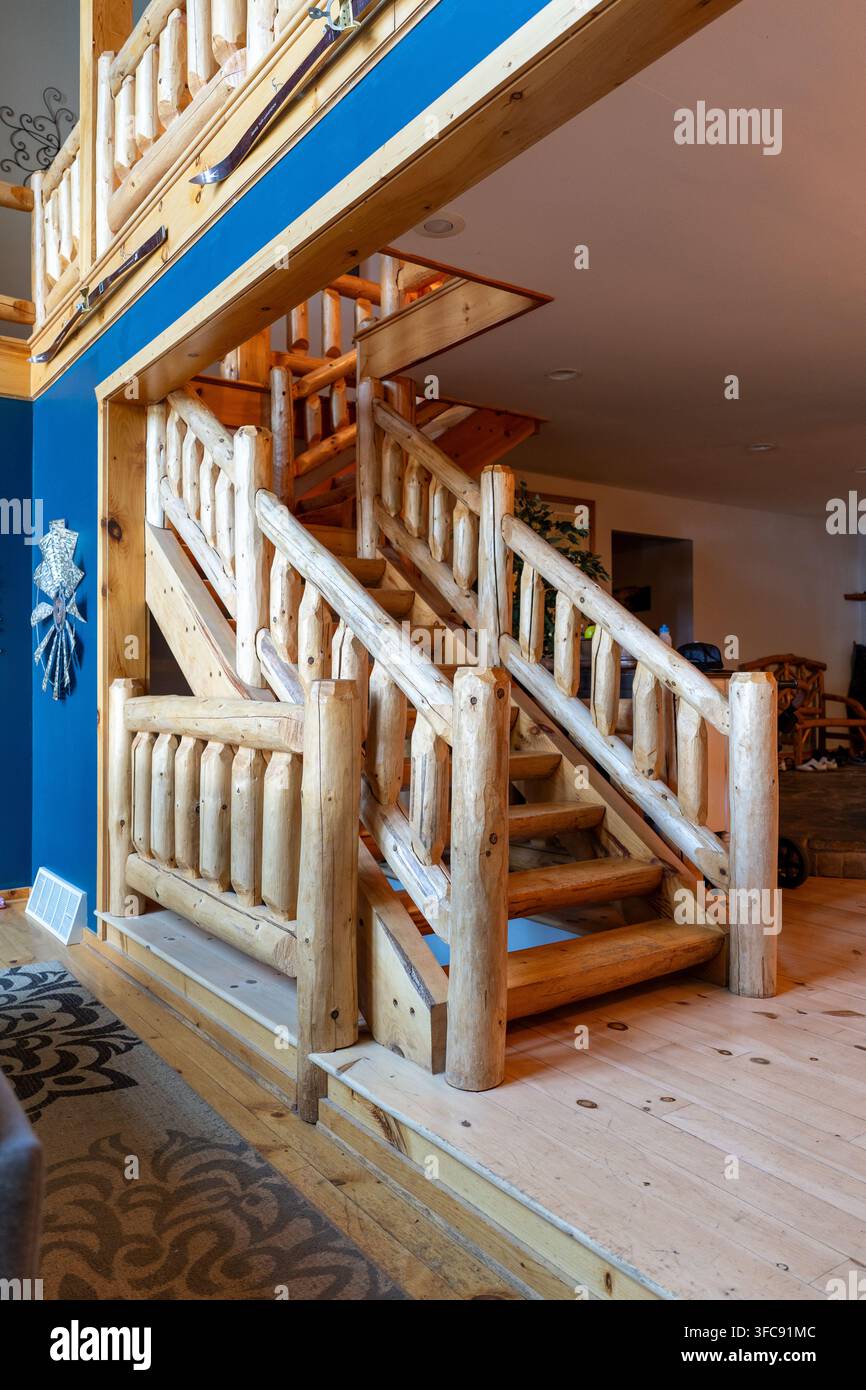 Vertikale Innenansicht einer rustikalen Holztreppe mit handgefertigten Baumstamm-Geländern in einem Häuschen im Cabin-Stil. Natürliche Holzkonstruktion, freiliegendes Holz Stockfoto