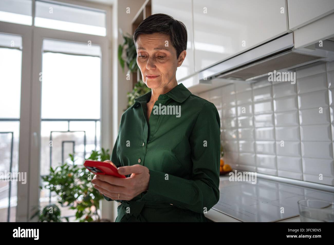 Ältere traurige Frau liest SMS auf dem Handy, tief in Gedanken versunken, nachdenklich, verwirrt und besorgt aussehend Stockfoto