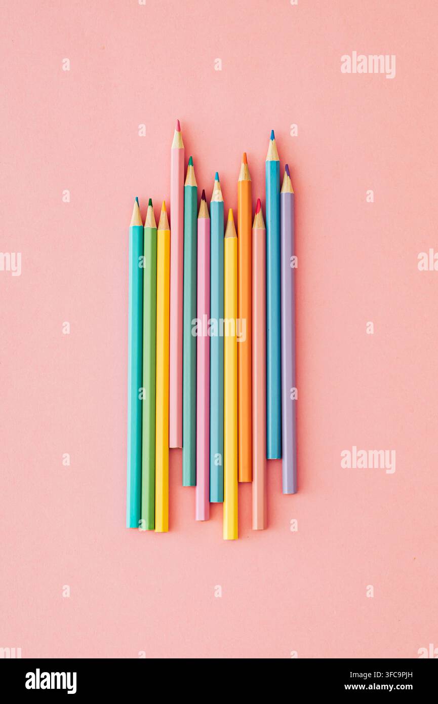 Bunte Farbstifte auf pastellrosa Hintergrund. Minimales Schul- und kreatives Bildungskonzept. Flat-Lay-Stil. Oberansicht. Stockfoto