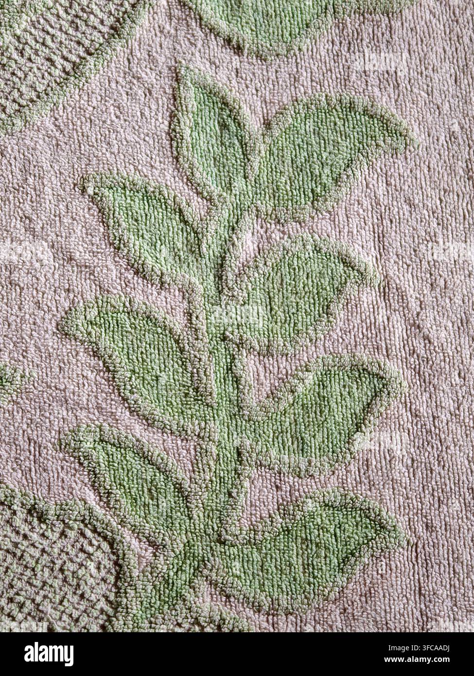 Weiches Baumwoll-Frotteehandtuch mit kompliziertem Blatt- und Blumenmuster, weiche strukturierte Oberfläche in gedämpftem Grün und Creme ideal für Wohnkultur, Stockfoto