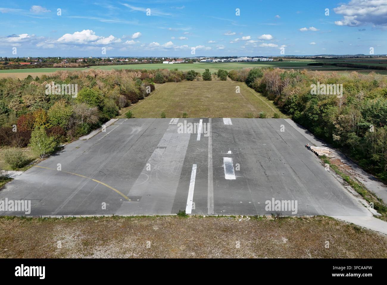 Verlorener Ort in München. Die verlassene Startbahn des ehemaligen Flughafens München-Riem inmitten einer Herbstlandschaft. Das Luftbild zeigt ein verbliebenes Stück der alten asphaltierten Start- und Landebahn des ehemaligen Flughafens München-Riem. Die graue Asphaltfläche hat Stockfoto