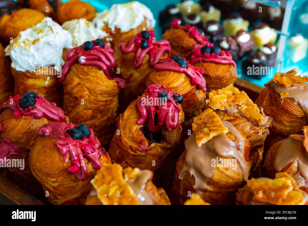 Holztablett mit verschiedenen süßen Cruffins, die mit einer Auswahl an Cremes belegt sind. Stockfoto