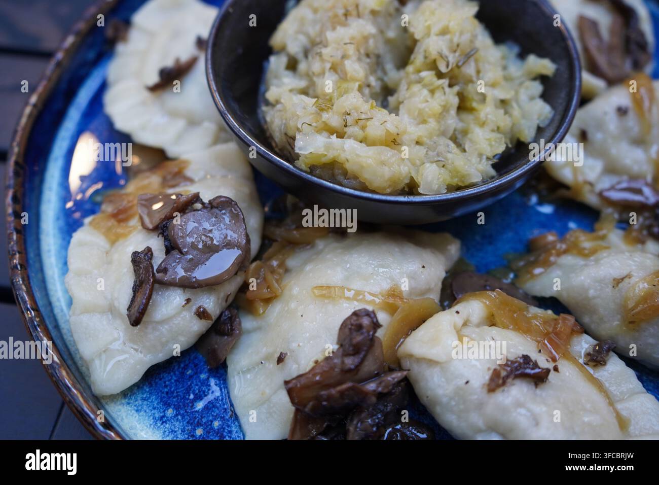 Nahaufnahme von traditionellen Pierogi-Teigtaschen gefüllt mit Rind-, Schwein- und Entfleisch mit getrockneten Preiselbeeren und gebratener Kohlrabi. Authentische polnische Küche. Stockfoto