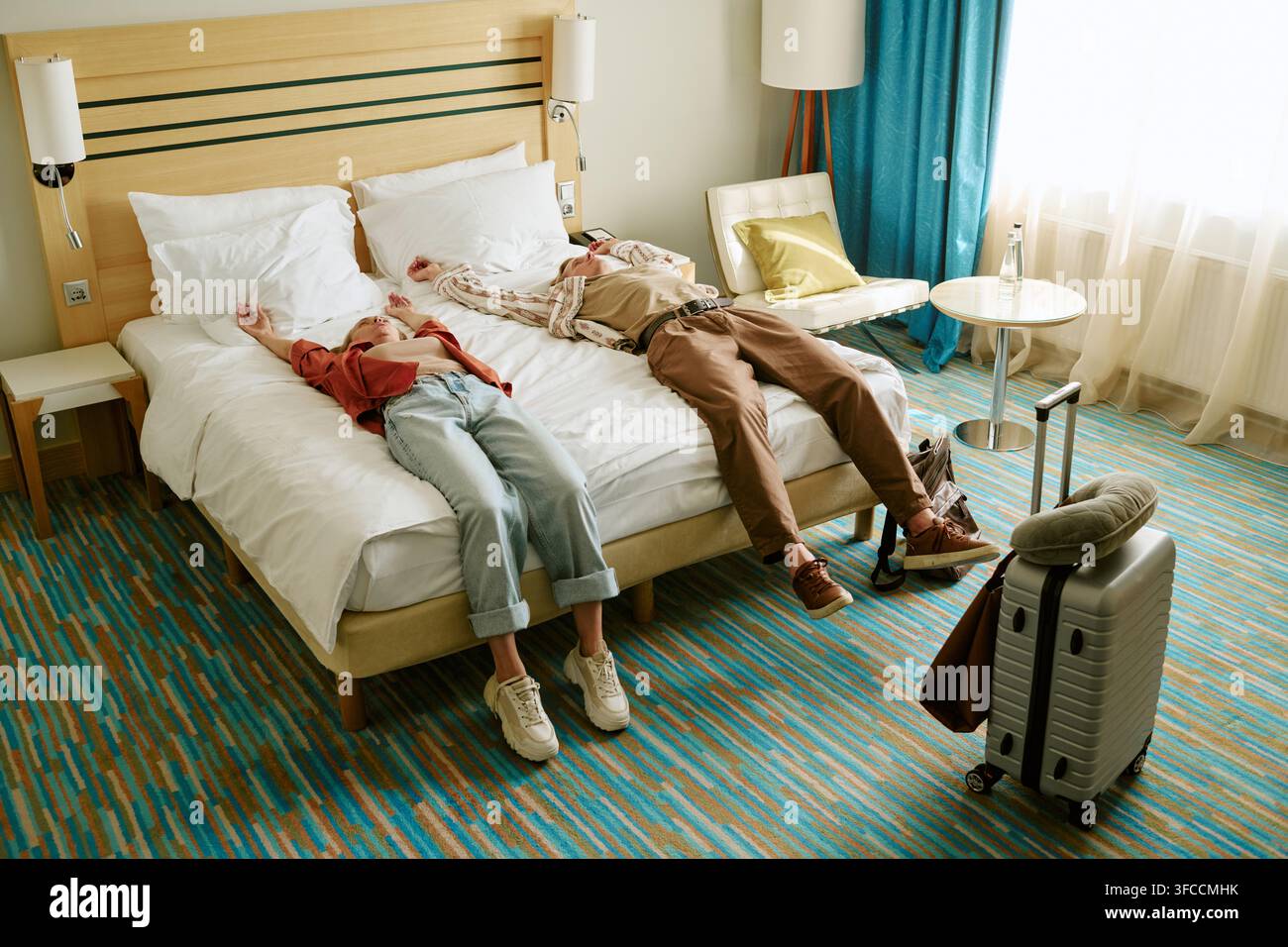 Mann und Frau liegen auf dem Bett im Hotelzimmer nach einer langen Reise Stockfoto