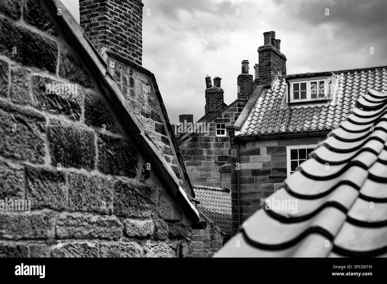 Schwarzweißansicht von historischen Steinhäusern, Ziegeldächern und Ziegelschornsteinen im alten Fischerdorf Robin Hood’s Bay, North Yorkshire, En Stockfoto