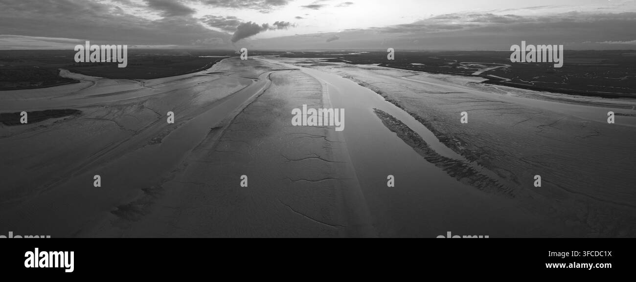 Monochromer Blick auf eine weite Flusslandschaft mit Sandbänken und bewölktem Himmel. der Swale-Fluss, Kent UK Stockfoto