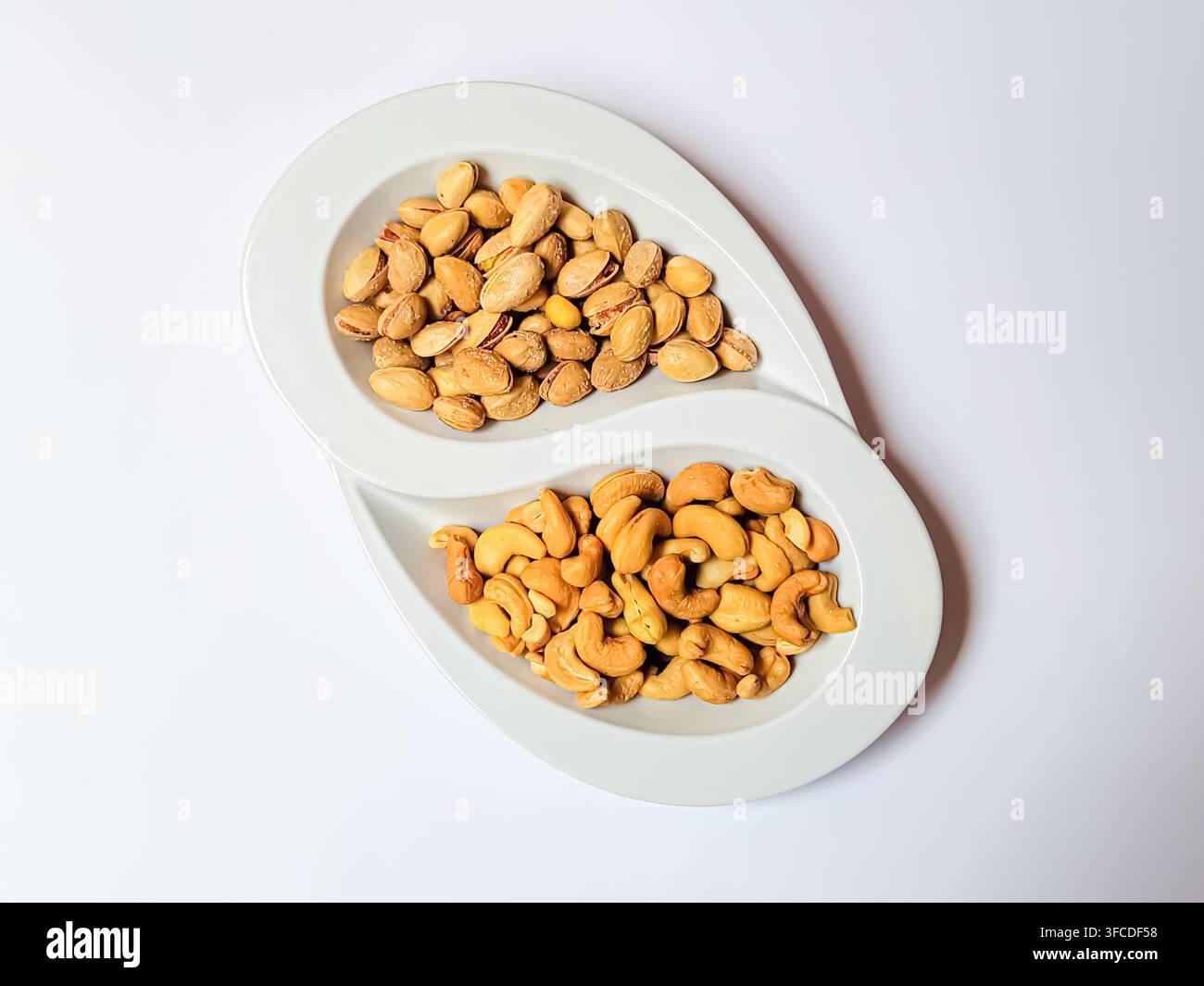 Abteilgericht mit Cashewnüssen und Pistazien auf weißem Hintergrund. Stockfoto