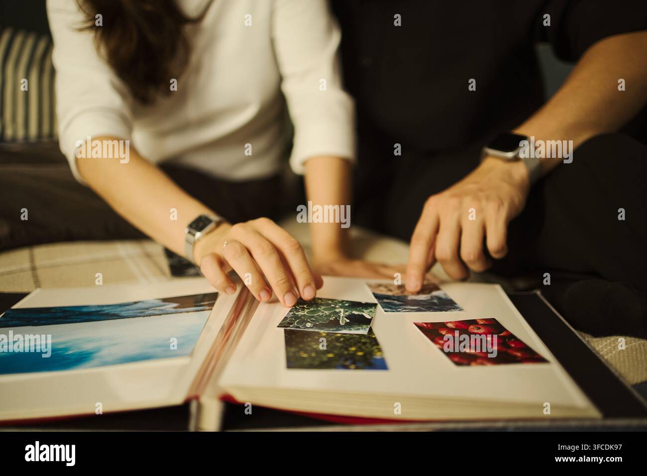 Zusammengeschnittene Aufnahme eines jungen Paares, das gedruckte Fotos in einem Album betrachtet und an Reiseerinnerungen zurückdenkt. Ideal für die Vermarktung von Familienlebensstil- und Fotografie-Dienstleistungen Stockfoto