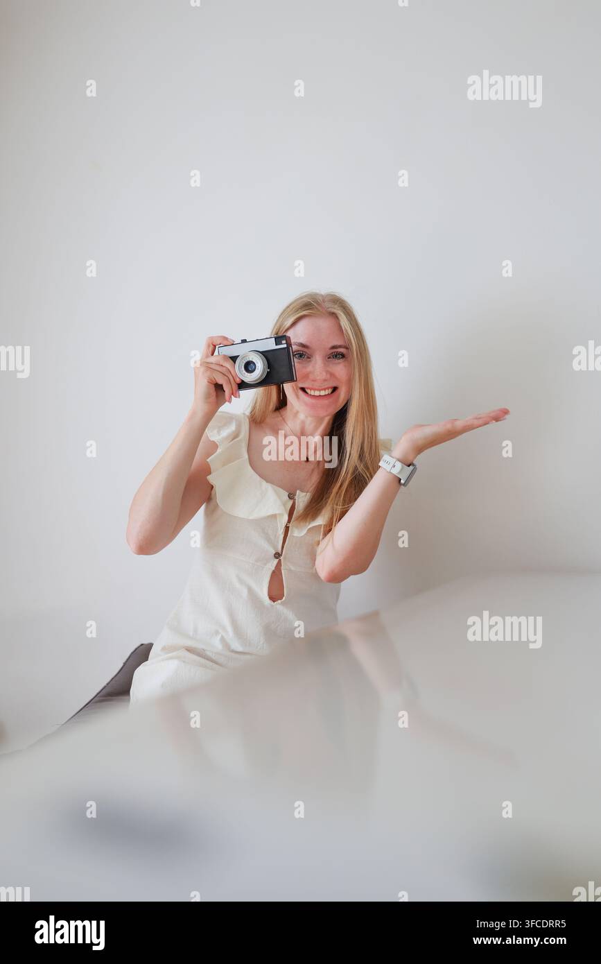 Junge blonde Frau mit Kompaktkamera lächelt in die Kamera, Fotografie, Kreativität und visuelles Storytelling-Konzept. Stockfoto