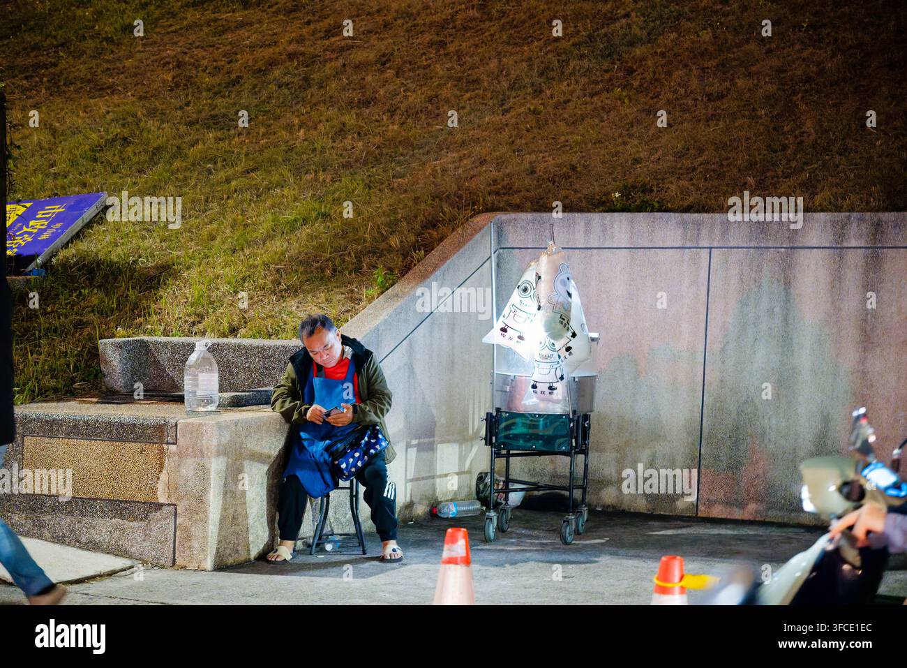 Neu-Taipeh, Taiwan – 19. Feb. 2026: Nachtszene eines älteren Händlers, der selbstgemachte Zuckerwatte an einer Flusseck Ecke im Park von Neu-Taipeh verkauft Stockfoto